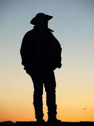 Photo of a cowboy in front of the sunset